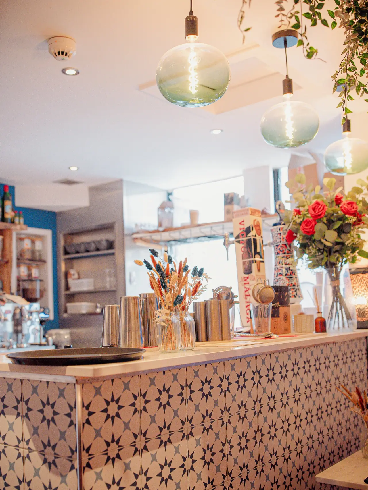 The tiled bar with flowers, glassware and bottles behind