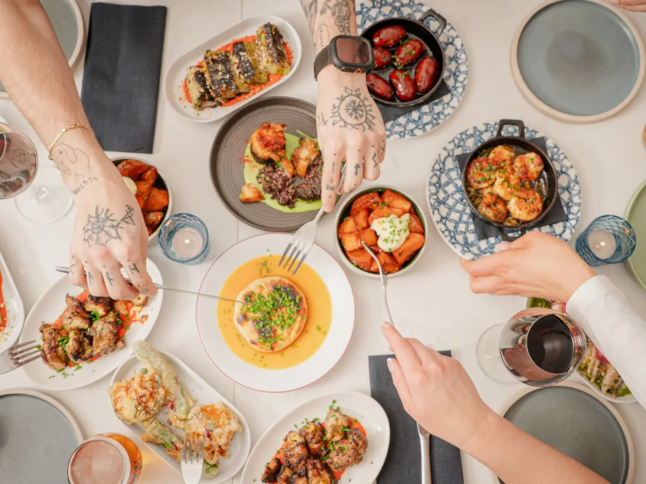 Hands reaching across a table of small plates