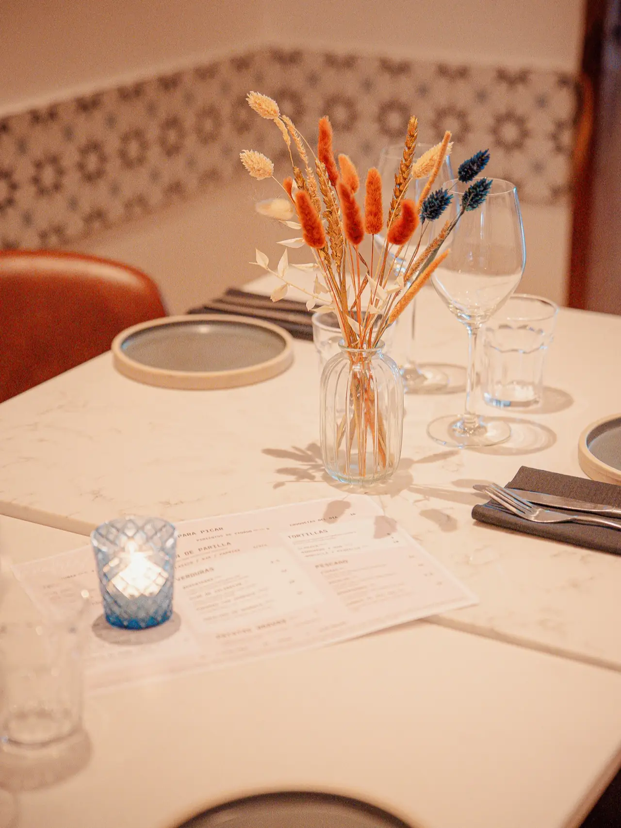 A table laid with candles and dried flowers against the blue star tiles